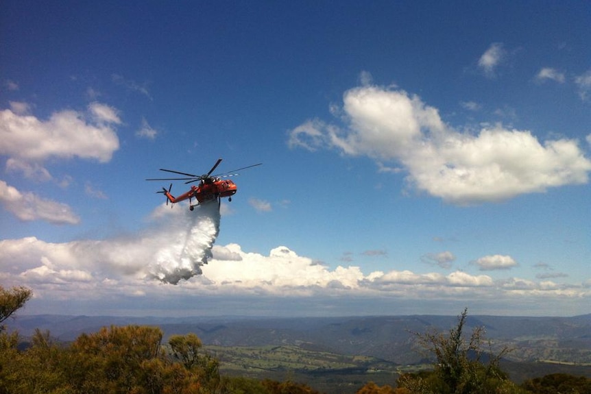 An RFS helicopter completes another water bombing sweep at a bushfire in Katoomba