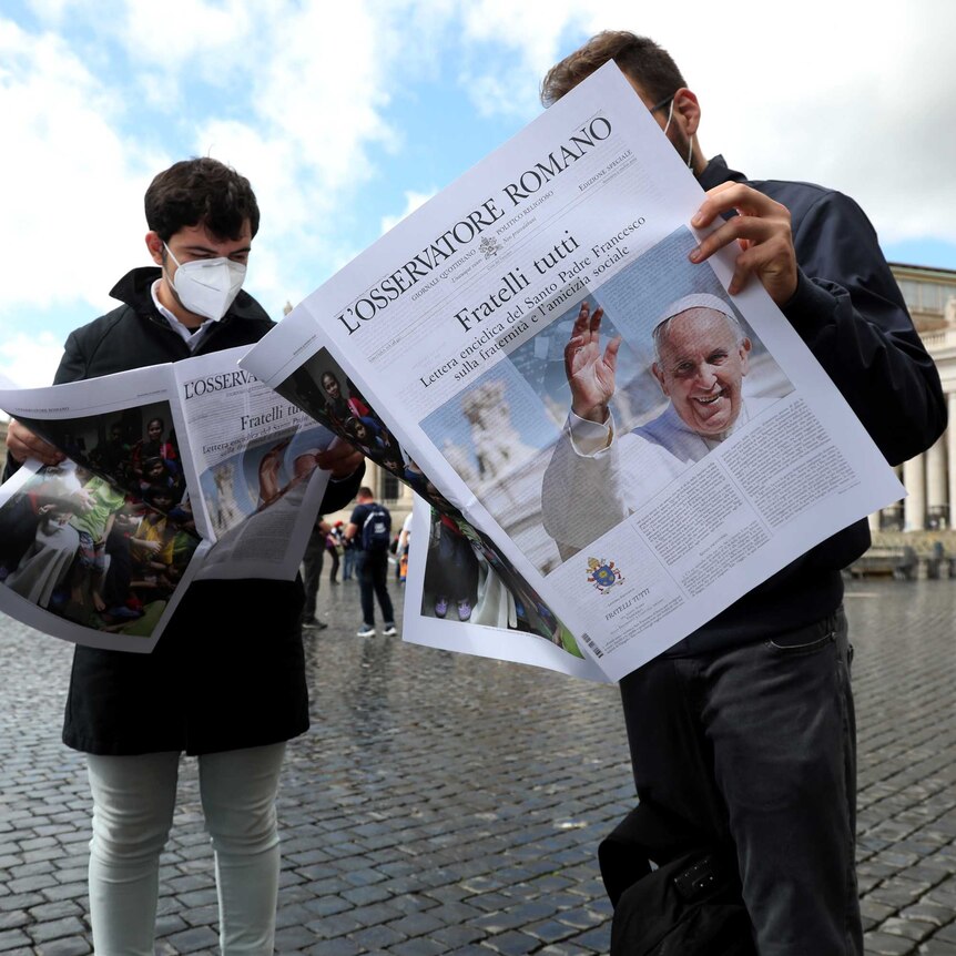 People reading a special edition of Vatican newspaper L'Osservatore Romano containing the new Encyclical.