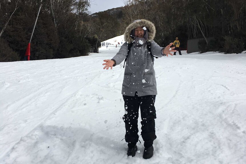 Seorang perempuan sedang berdiri dan bermain salju