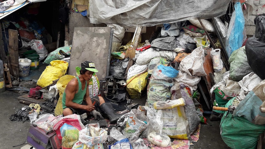 A man sorting the garbage he has collected right outside his home.