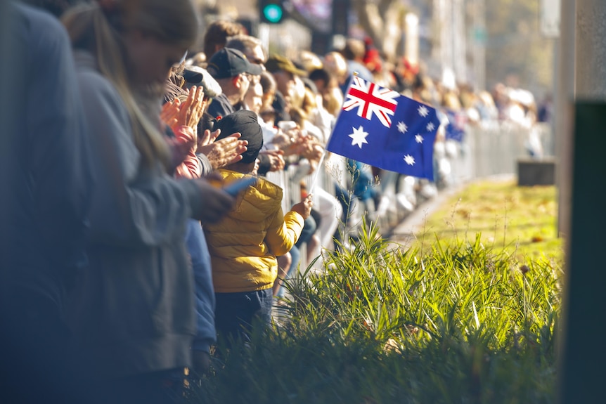 A small boy with a turban waves an Australian flag.