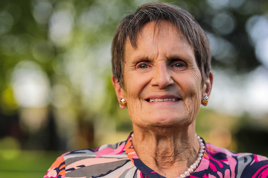 A woman dressed in pink smiles at the camera.