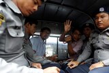 Reuters journalists Wa Lone and Kyaw Soe Oo sit beside police officers in the back of a vehicle.