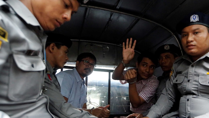 Reuters journalists Wa Lone and Kyaw Soe Oo sit beside police officers in the back of a vehicle.