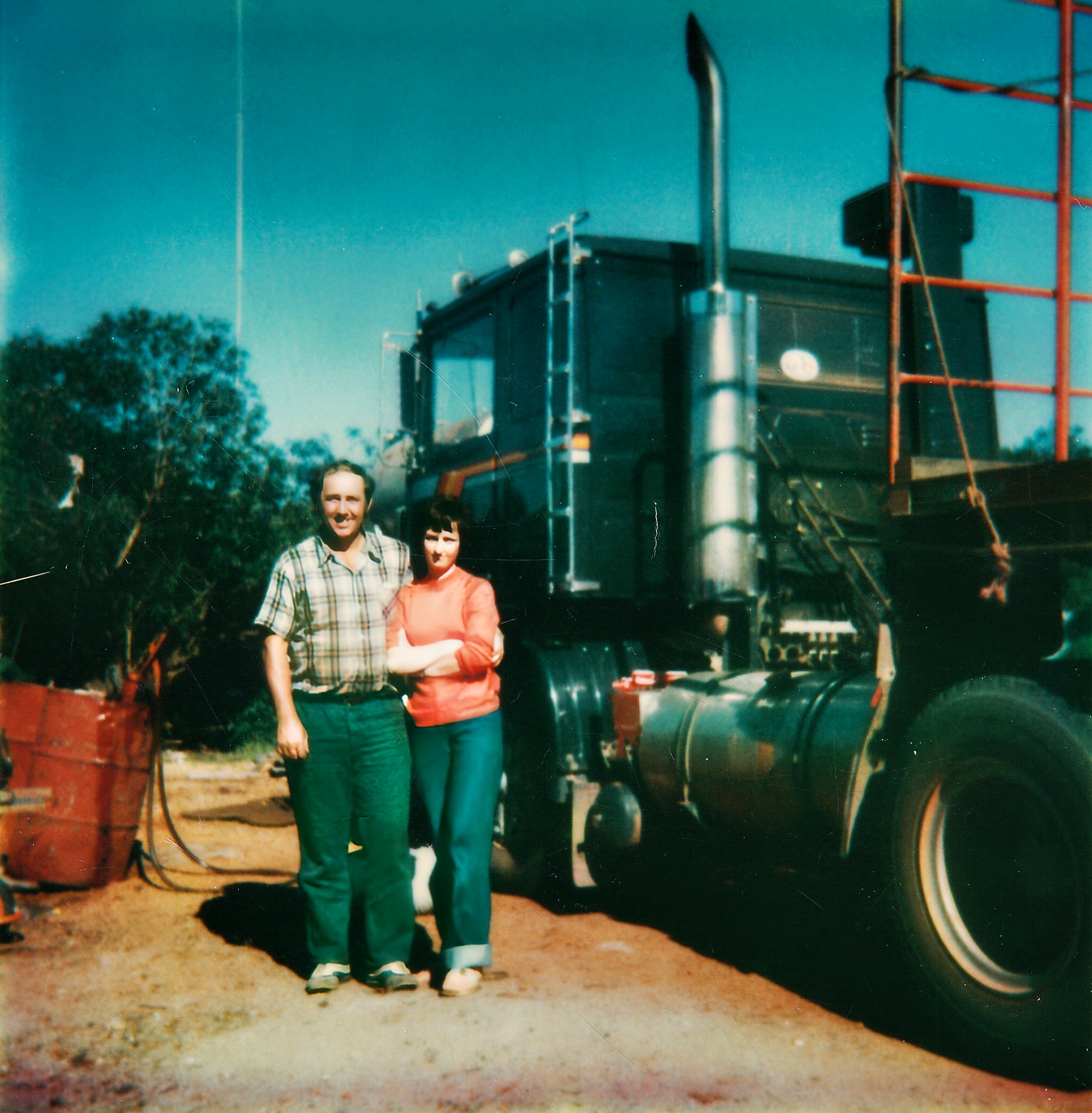 Foto antigua de Terry y Maree parados frente a un gran camión negro.