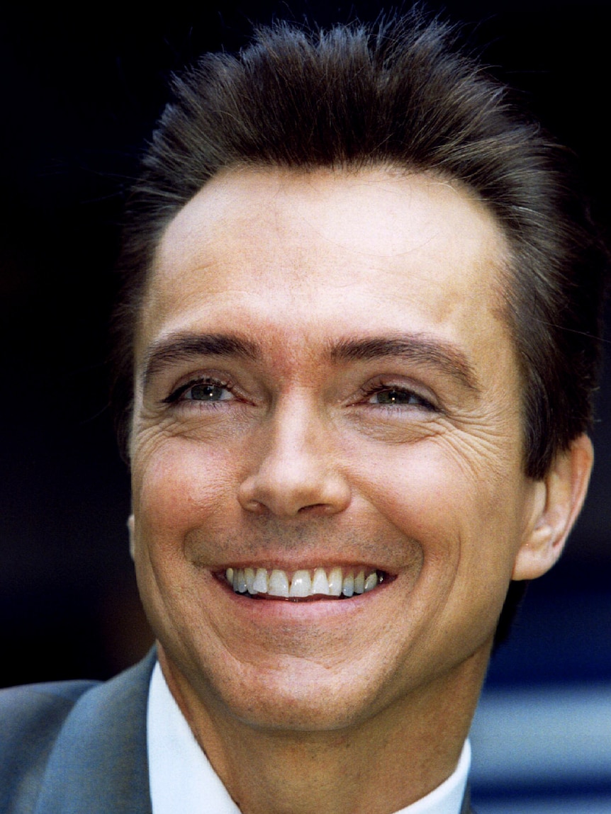 A smiling profile photo of David Cassidy, smiling and wearing a suit