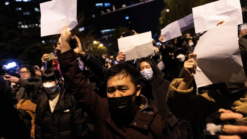 一群人戴着口罩 手举白纸在路旁抗议