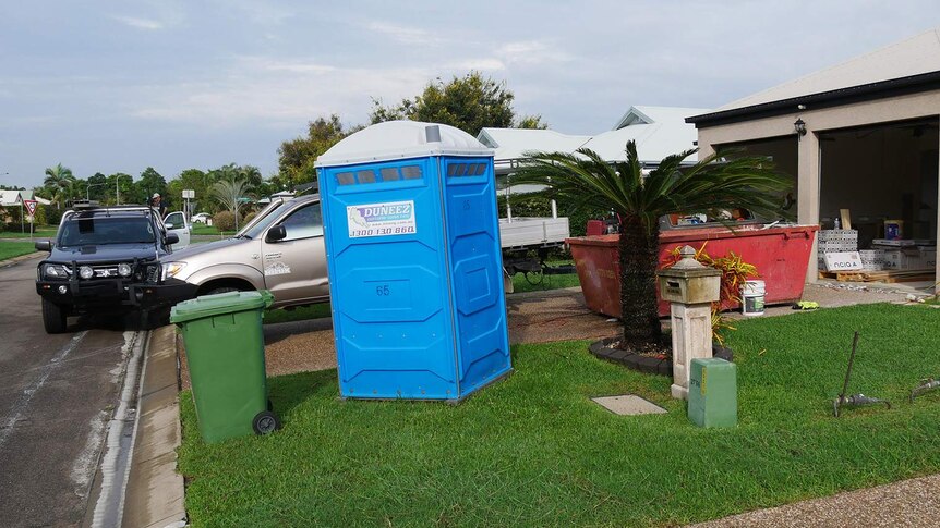 A skip bin and port-a-loo outside a home in the Townsville suburb Fairfield Waters where tradesmen are completing flood repairs