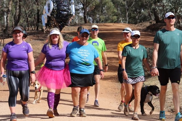 Suzanne Crane and her friends walk in a group on a dirt track.