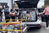 A car being loaded with scores of large boxes of Lego.