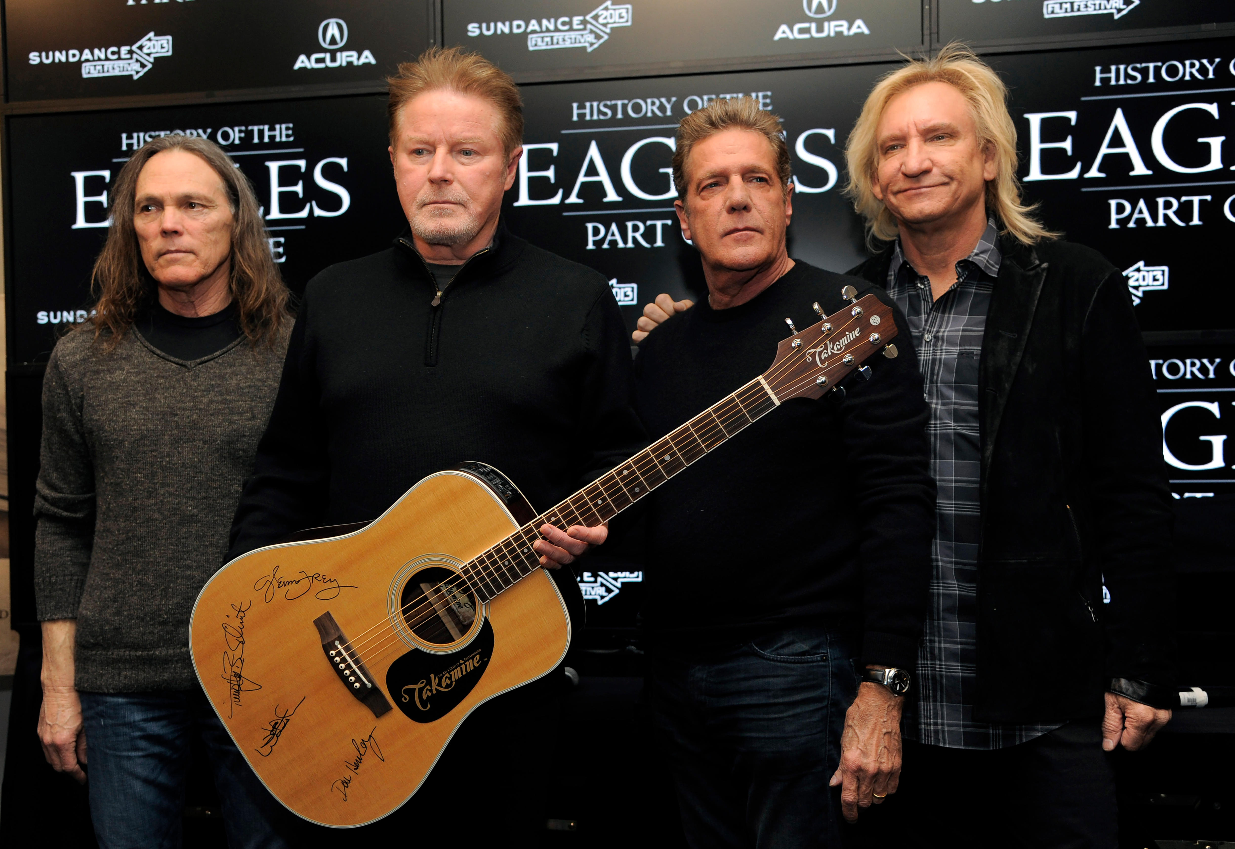 Four of the Eagles members with a signed guitar