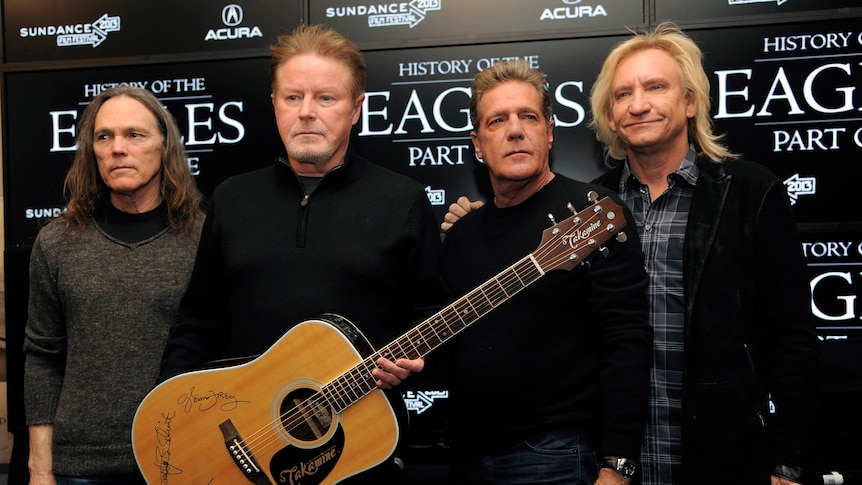 Four of the Eagles members with a signed guitar