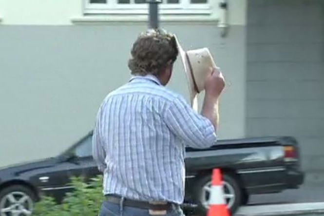 Queensland South Burnett farmer Wayne Robert Green hides his face with his hat when leaving court in Brisbane in March 2, 2020.