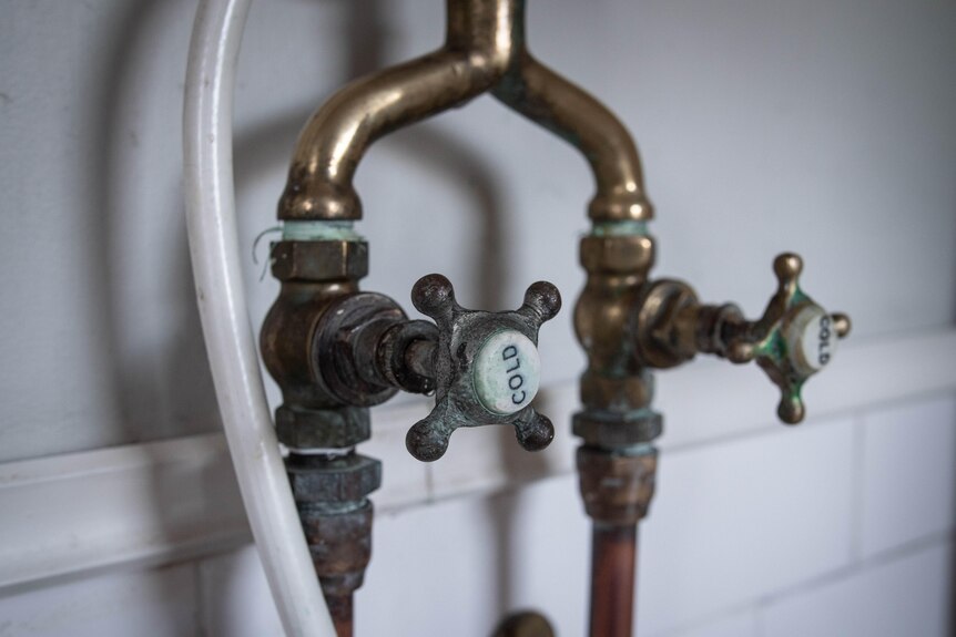 A close-up on a cold tap shows brass fixtures with green and rust marks in places
