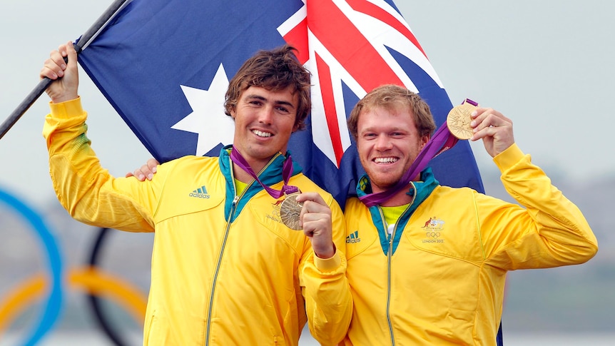 Iain Jensen and Nathan Outteridge hold up their gold medals, claimed in the 49er sailing class.