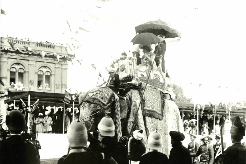 A black and white photo of people riding an elephant in New Delhi.