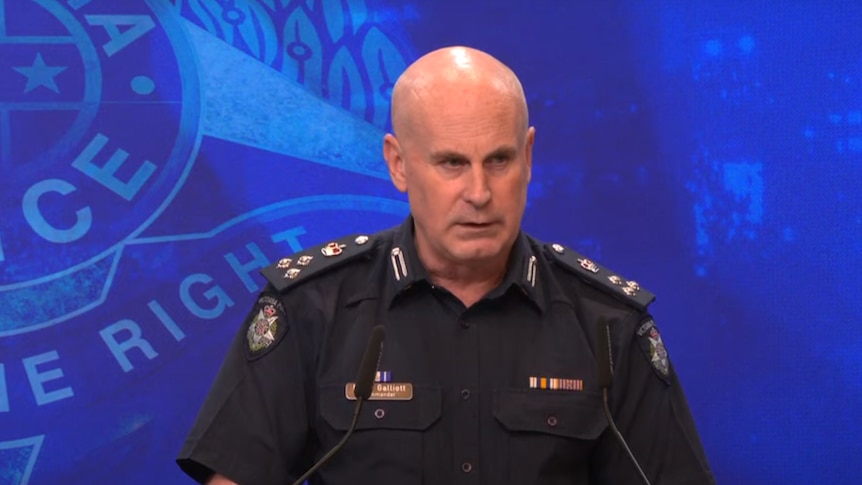 A bald police officer speaks at a podium.