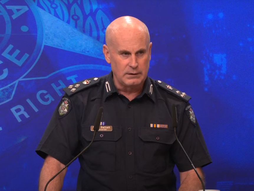 A bald police officer speaks at a podium.