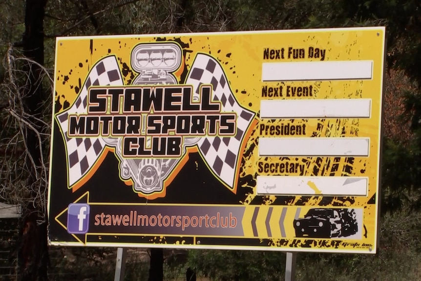 A yellow sign with chequered flags and a symbol with the words Stawell Motor Sports Club.