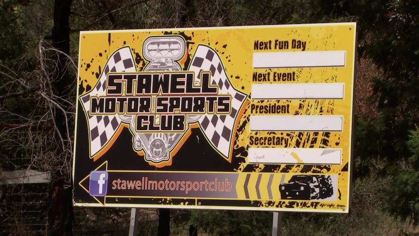 A yellow sign with chequered flags and a symbol with the words Stawell Motor Sports Club.
