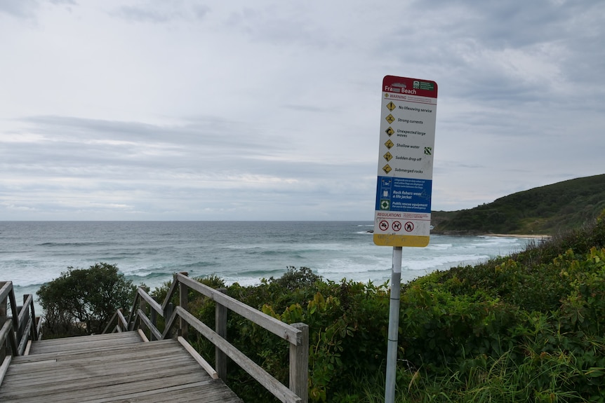 A safety sign for Frazer Beach and the beach vista in the background