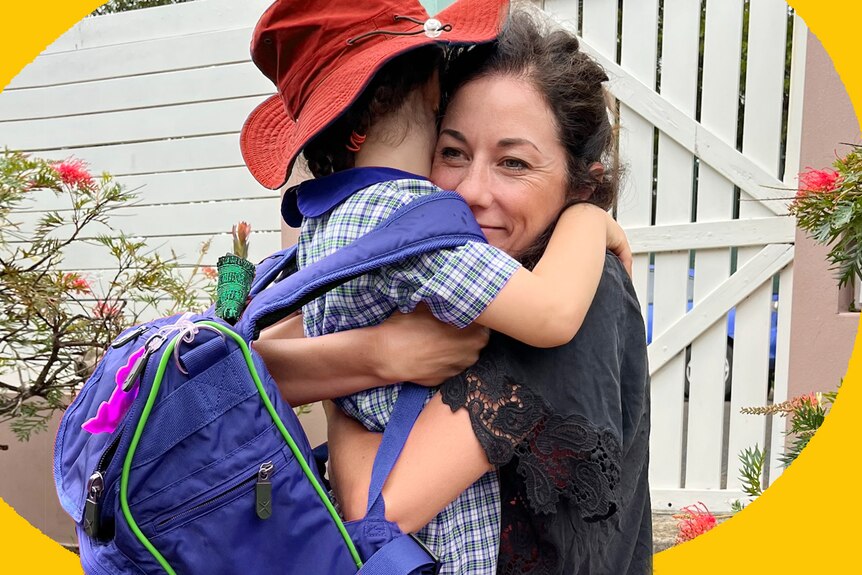 Veronica Milsom hugging her daughter who's wearing a school uniform, bag and hat.