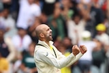 Australia bowler Nathan Lyon cheers and clenches both fists while on the field in front of the MCG crowd.