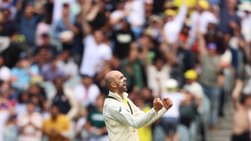 Australia bowler Nathan Lyon cheers and clenches both fists while on the field in front of the MCG crowd.