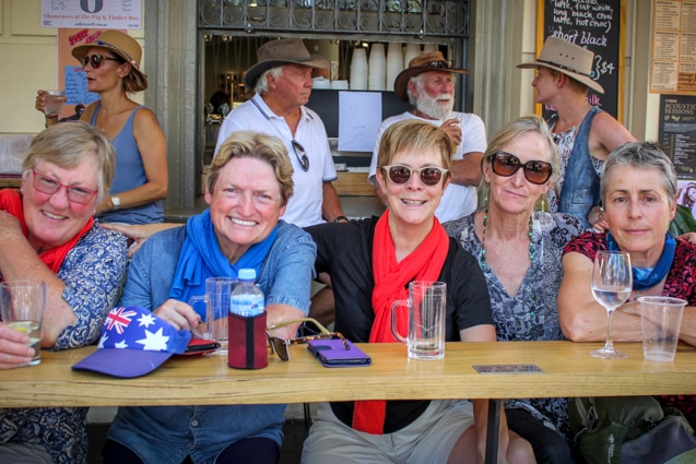 Five women sitting together at an outdoor bar having a drink