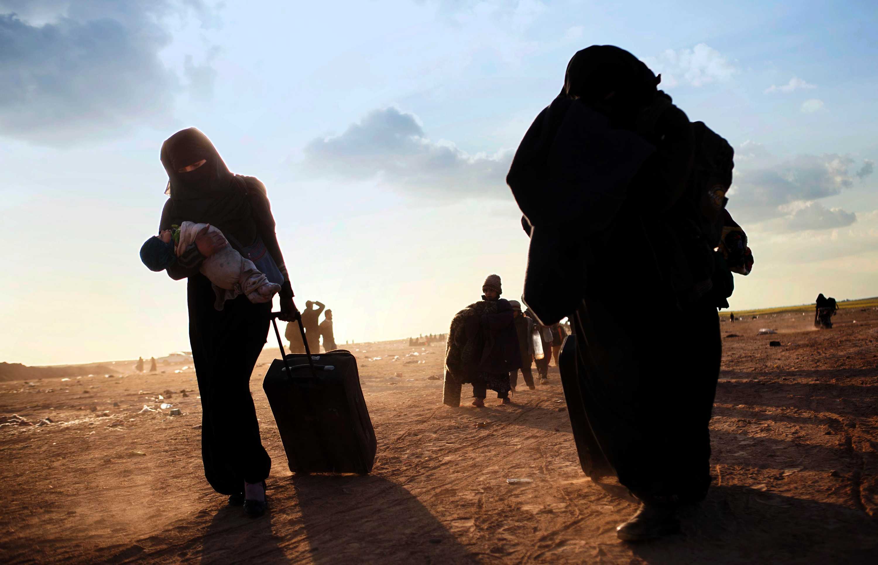 Women and children arrive at a screening point near Baghouz, Syria