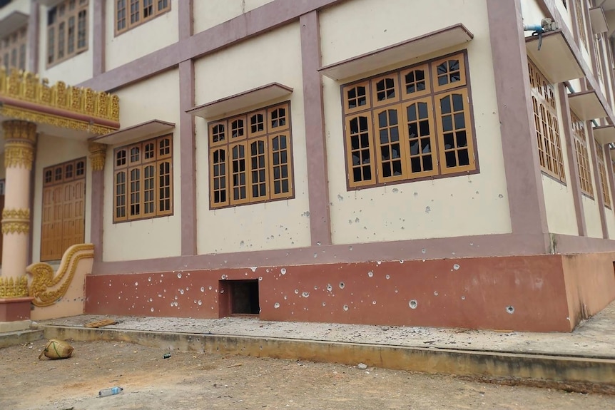 Pockmarks from bullets can be seen low on the wall of a Buddhist monastery.