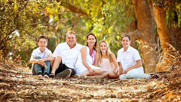 Kym Curnow, who died in a bushfire near Esperance, pictured with his wife and three children sitting on the ground.