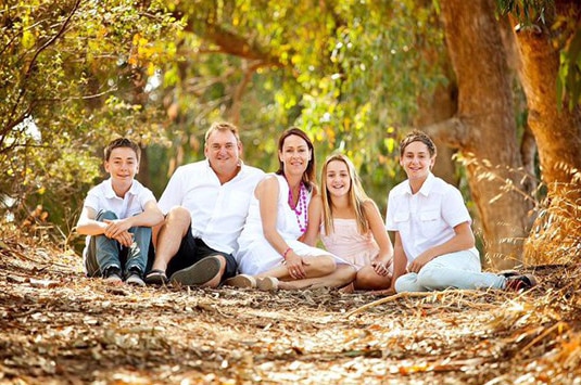 Kym Curnow, who died in a bushfire near Esperance, pictured with his wife and three children sitting on the ground.