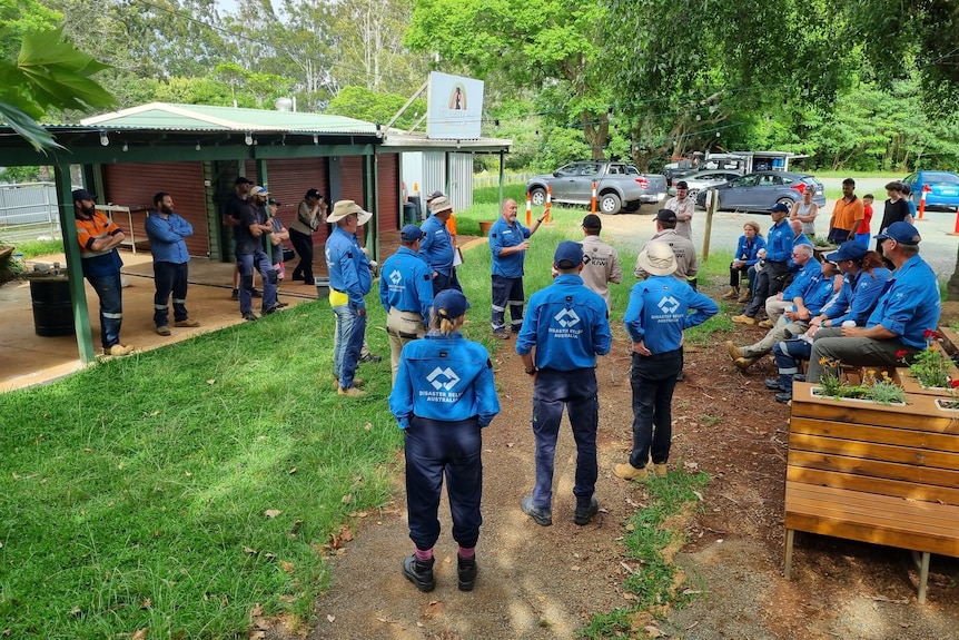 A group of people in blue 'disaster recovery Australia' shirts talking