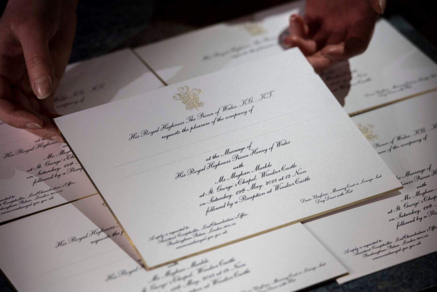 White invitation with black writing and gold stamp