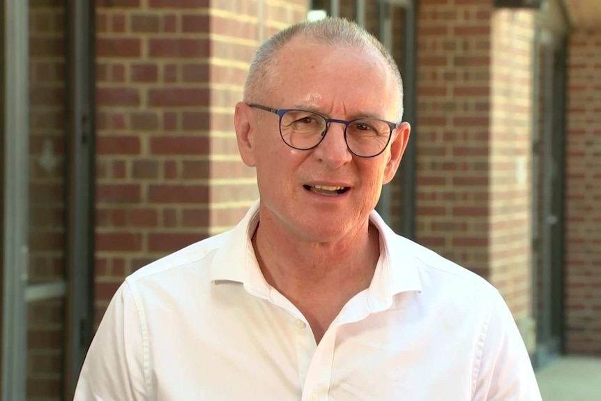 A middle-aged man with spectacles and a bald head