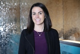 Kate Fitz-Gibbon looking straight at the camera and smiling, wearing a black jacket