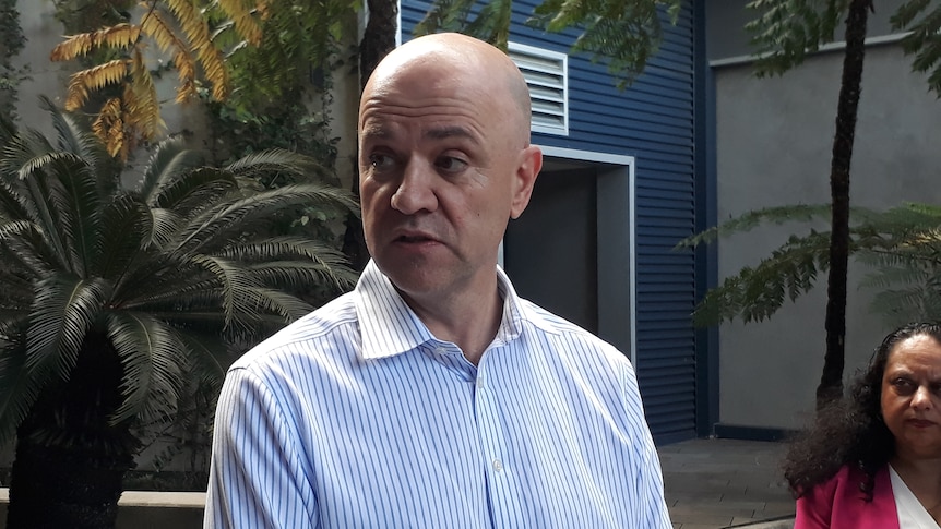 A middle aged man in a shirt outside a hospital