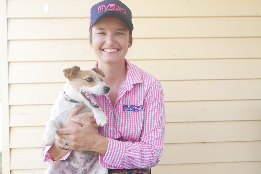 Zoe O'Brien smiles while holding a small dog.