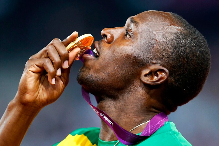 Usain Bolt poses with his gold medal on the podium after doing the double again.