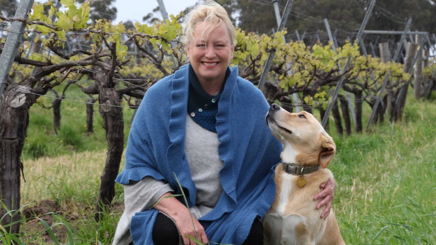 Vanya Cullen with dog in front of grapevines