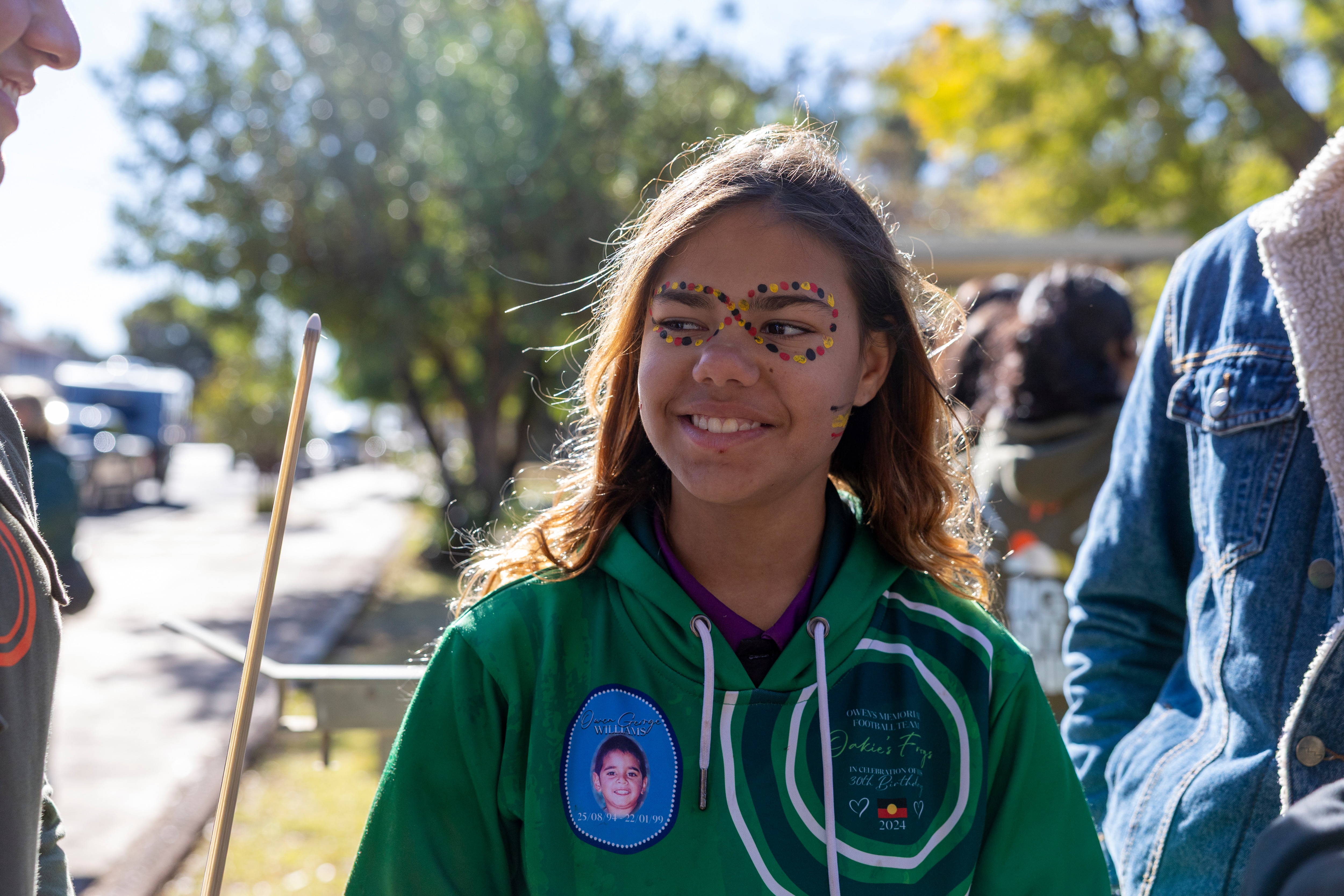 A young girl with red, black and yellow paint around her eyes.