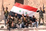 Soldiers pose with the Syrian flag