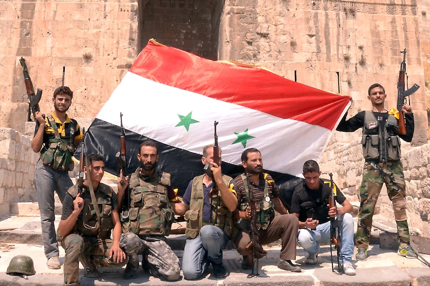 Soldiers pose with the Syrian flag