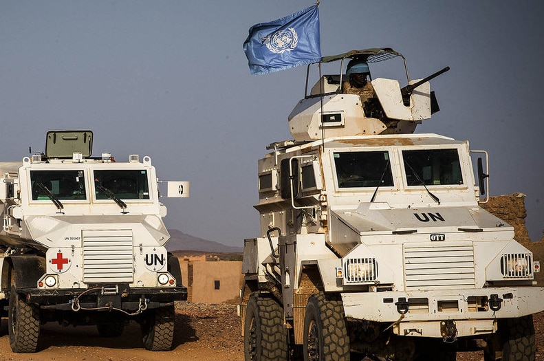 Three heavily armoured vehicles with the UN flag travel through Mali