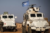 Three heavily armoured vehicles with the UN flag travel through Mali
