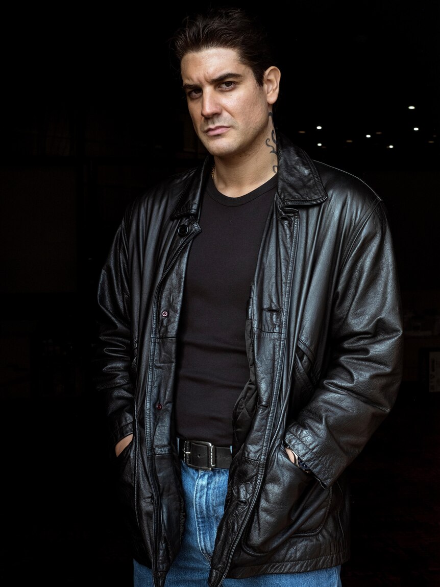 Claude Jabbour as Sam Ibrahim with a neck tattoo and leather jacket over black shirt