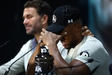 Anthony Joshua holds his head in his hands and has Eddie Hearn hold the back of his head