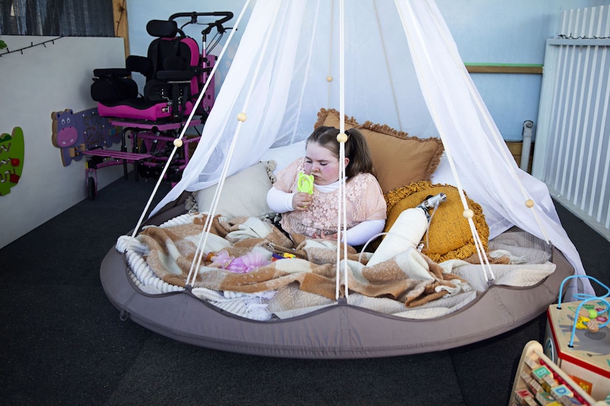 She sits among cushions and rugs with netting draped around her