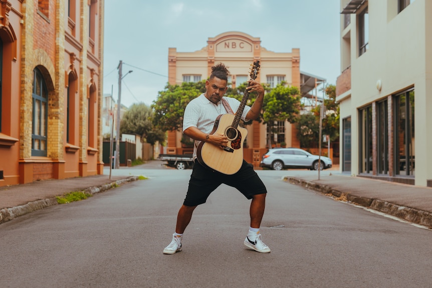 A man strikes a pose with a guitar.